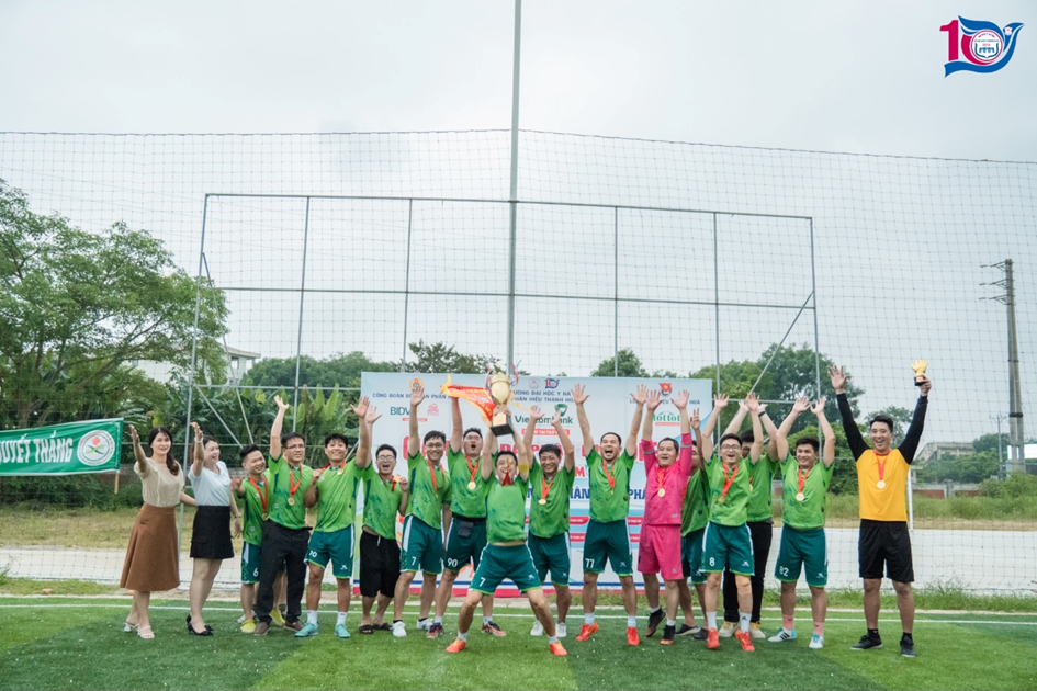 A group of people standing on a field holding up a trophy

Description automatically generated